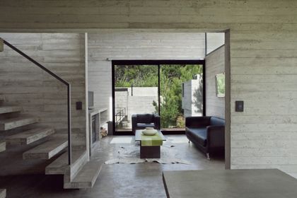 Living minimalista con doble altura, hormigón y grandes ventanales verdes — proyecto Conjunto V + D, por Luciano Kruk