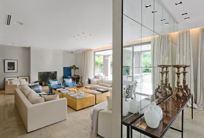 Living comedor moderno con luz natural, paredes espejadas y sofás amplios — proyecto Casa H, por Estudio Dado, en Belgrano