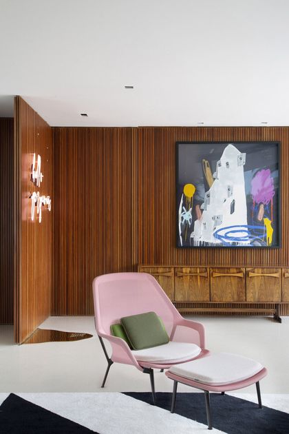 Living con sillón rosa, madera vertical y arte contemporáneo — proyecto BM House, por Studio Ro-ca