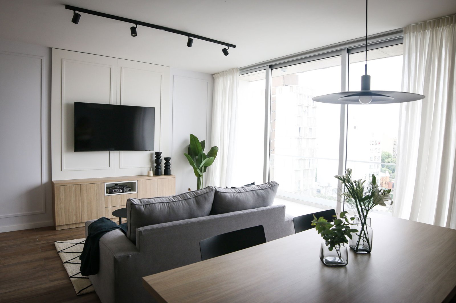 Sala de estar moderna com janelas do chão ao teto e luz natural — projeto Departamento Airbnb, por Jeitinho Estudió Creativo, em La Plata