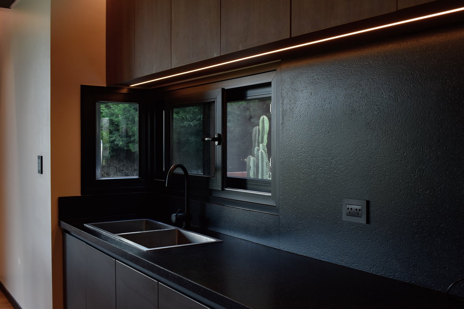 Cocina moderna oscura con isla y detalles de madera — proyecto CASA HC, por Daniel Daniele - Oficina de Arquitectura, en Canning