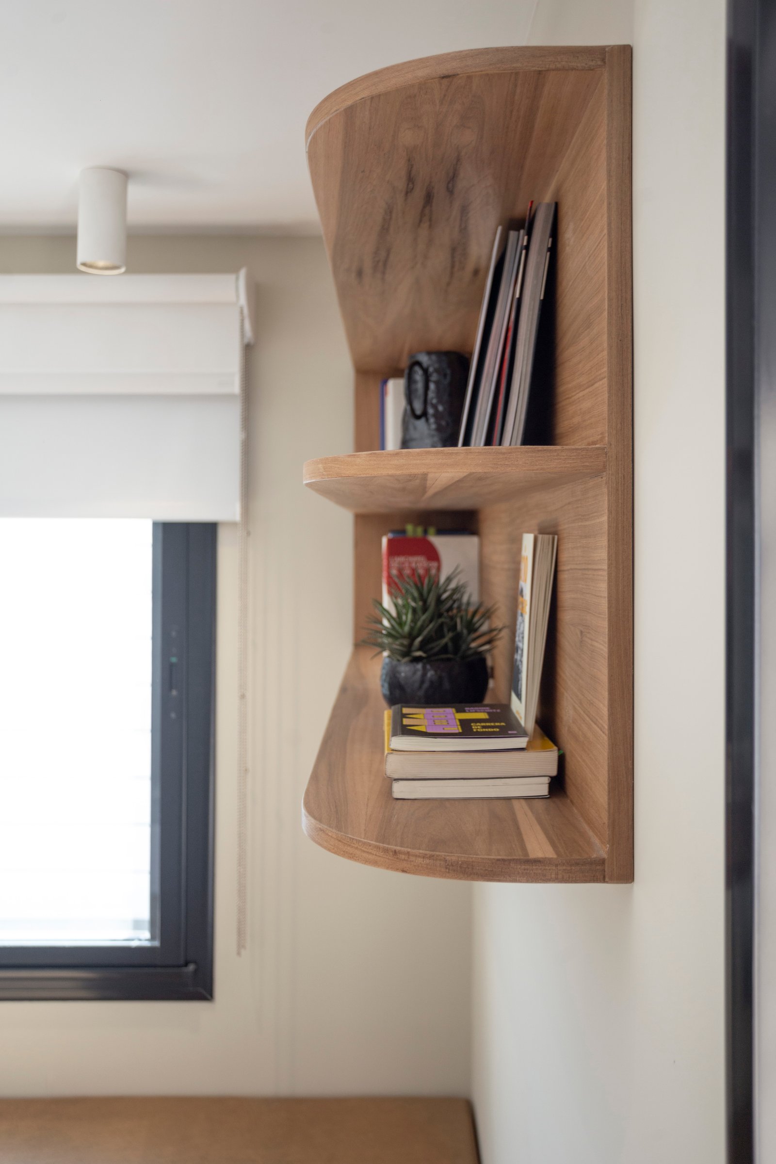 Estantería curva de madera natural en pared de interior moderno — proyecto LAPRIDA, por La Nave Arq., en Vicente López
