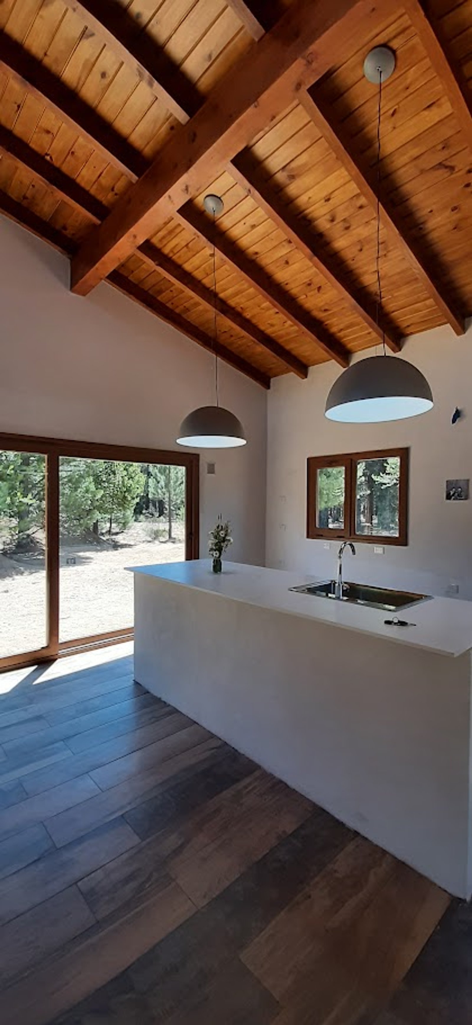 Cozinha rústica moderna com ilha branca e teto de madeira — projeto Proyecto Casa SZ, por Arquitecta Grace Overgaard, em Acceso Al Challhuaco