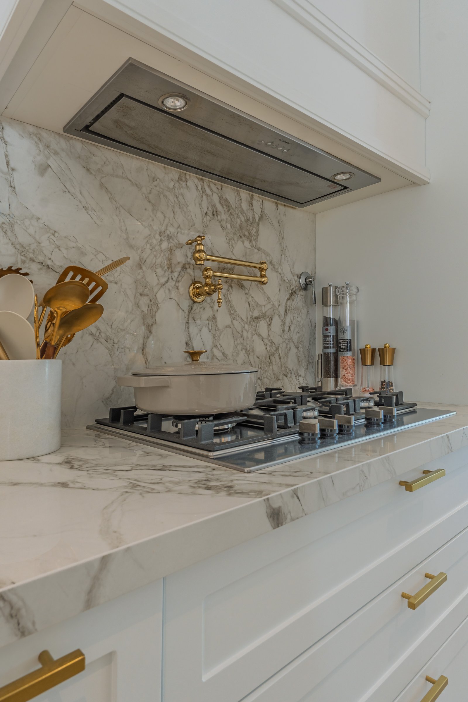 cocina moderna con mármol, extractor integrado y grifería dorada — proyecto Talar de Pacheco, por ABEJA CONCEPT, en Gral. Pacheco