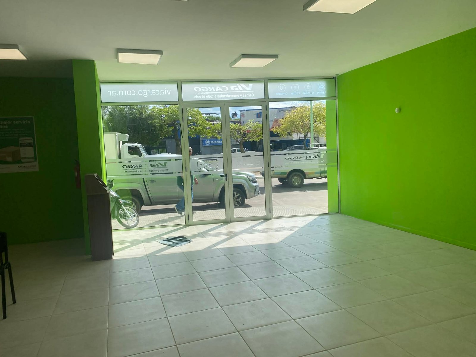 Espacio comercial interior moderno con paredes verdes y piso de baldosas — proyecto Sucursal Via Cargo, filial Corrientes, Empresa de distribución y logística., por Arquitecto Gust
