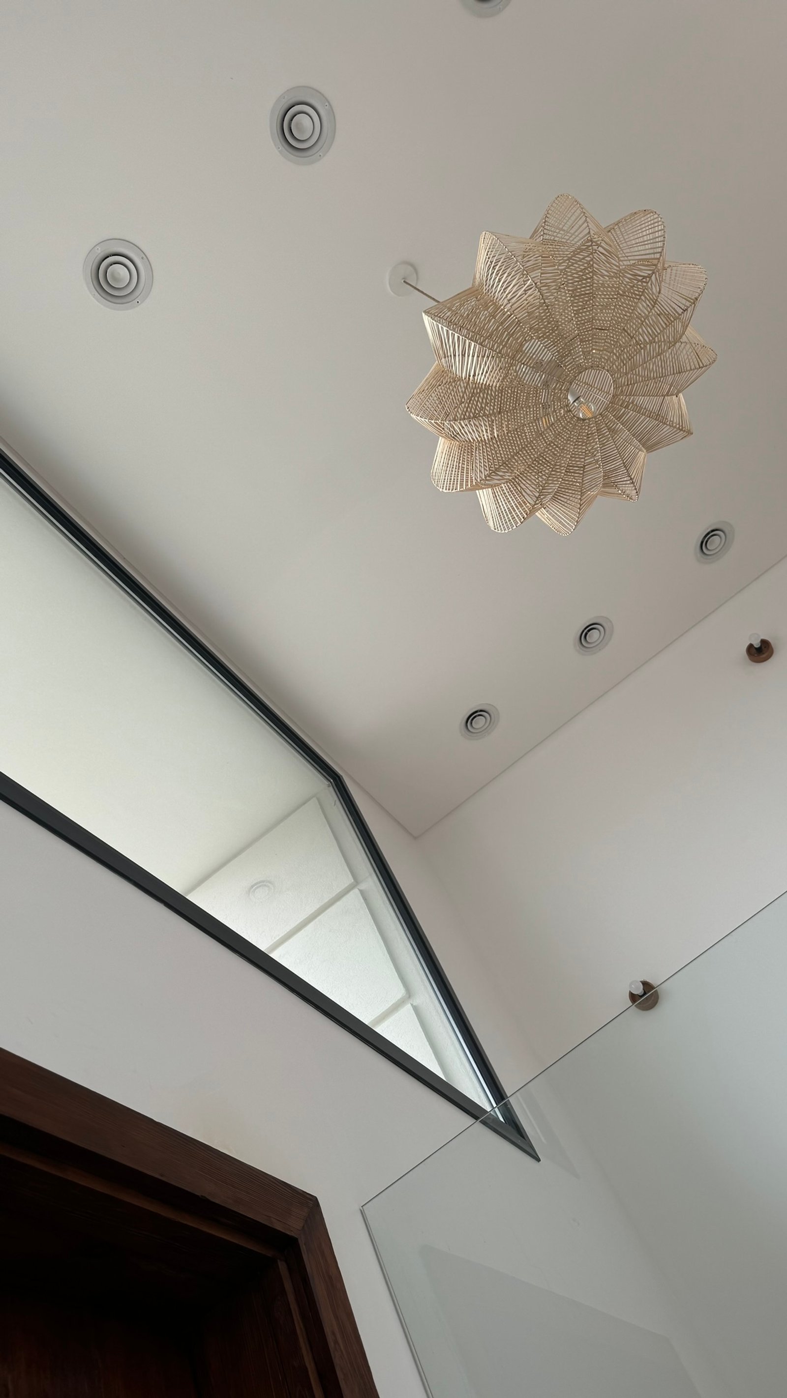 interior con lámpara colgante de mimbre y división de vidrio — proyecto Casa MC, por Hermann Arquitectos, en Bv. Central