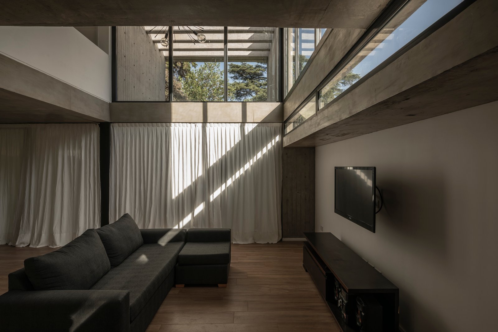 Living moderno con doble altura y ventanales — proyecto Casa Emilia, por Grupo CRBN, en Parque Leloir