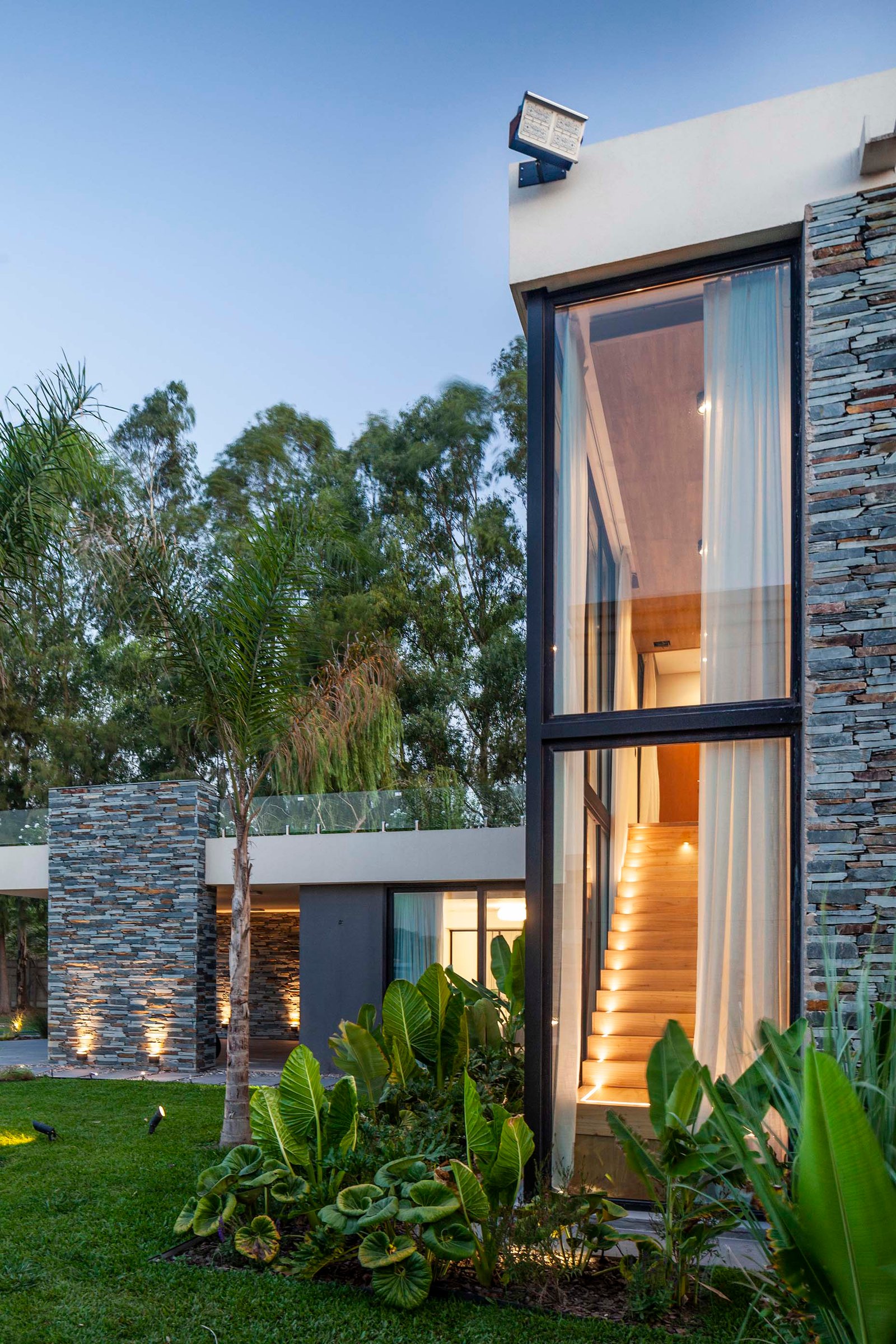 Fachada moderna com escadas de madeira e jardim tropical — projeto CASA T199, por A'PRIMA - Arquitectura Sustentable, em Los Robles 5901