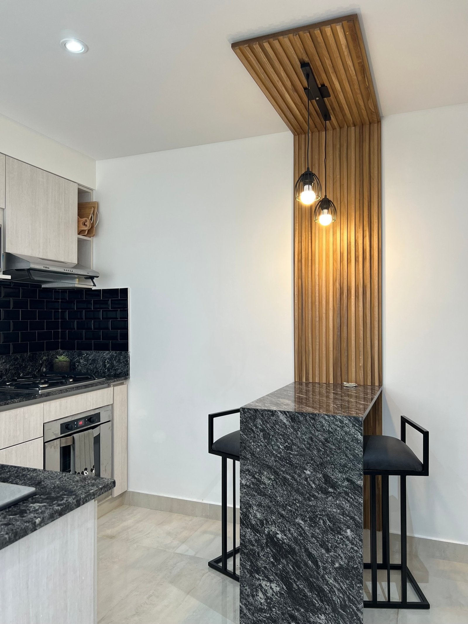 Cozinha moderna com ilha e bar, detalhes em madeira e pedra — projeto Basualdo I, por MDBK Arquitectura, em Liniers