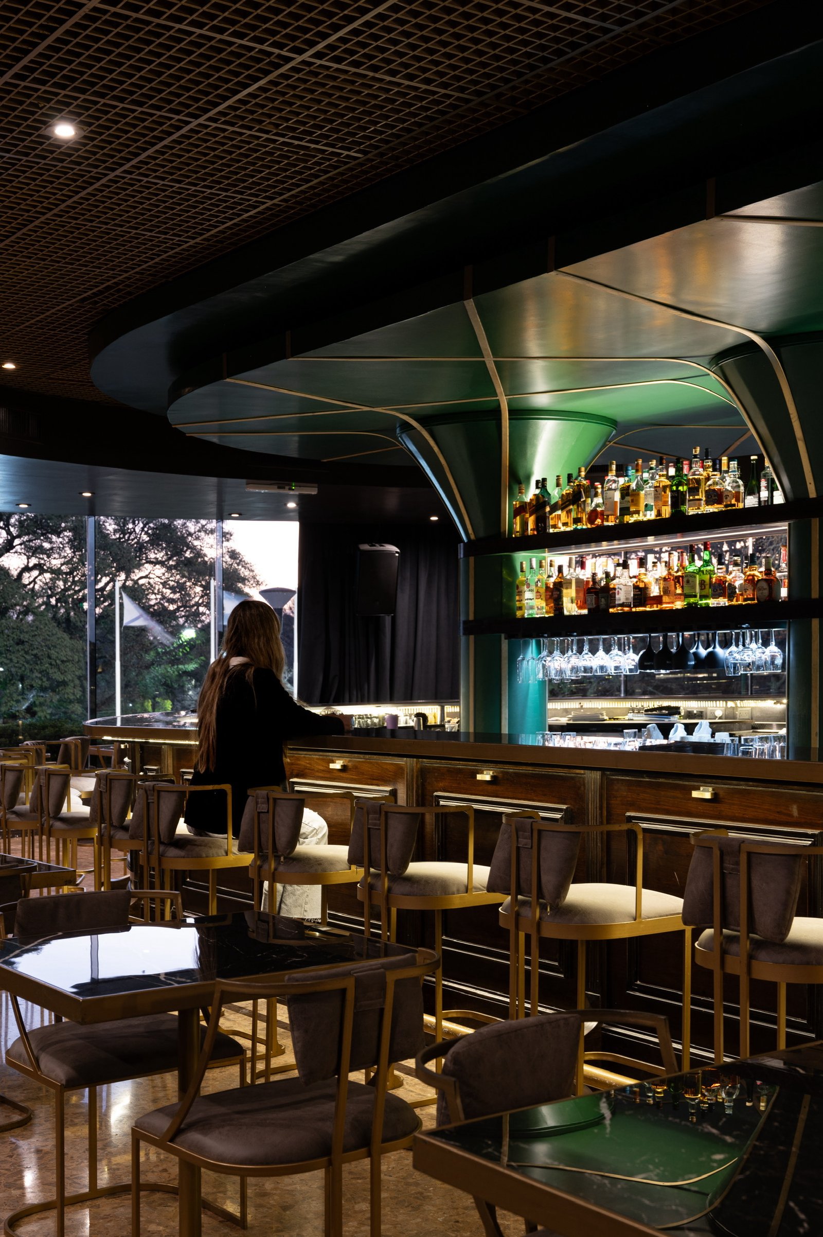Bar moderno con estanterías iluminadas y clientes sentados — proyecto PRESIDENTE BAR HIPODROMO, por AB ARQUITECTURA, en San Isidro