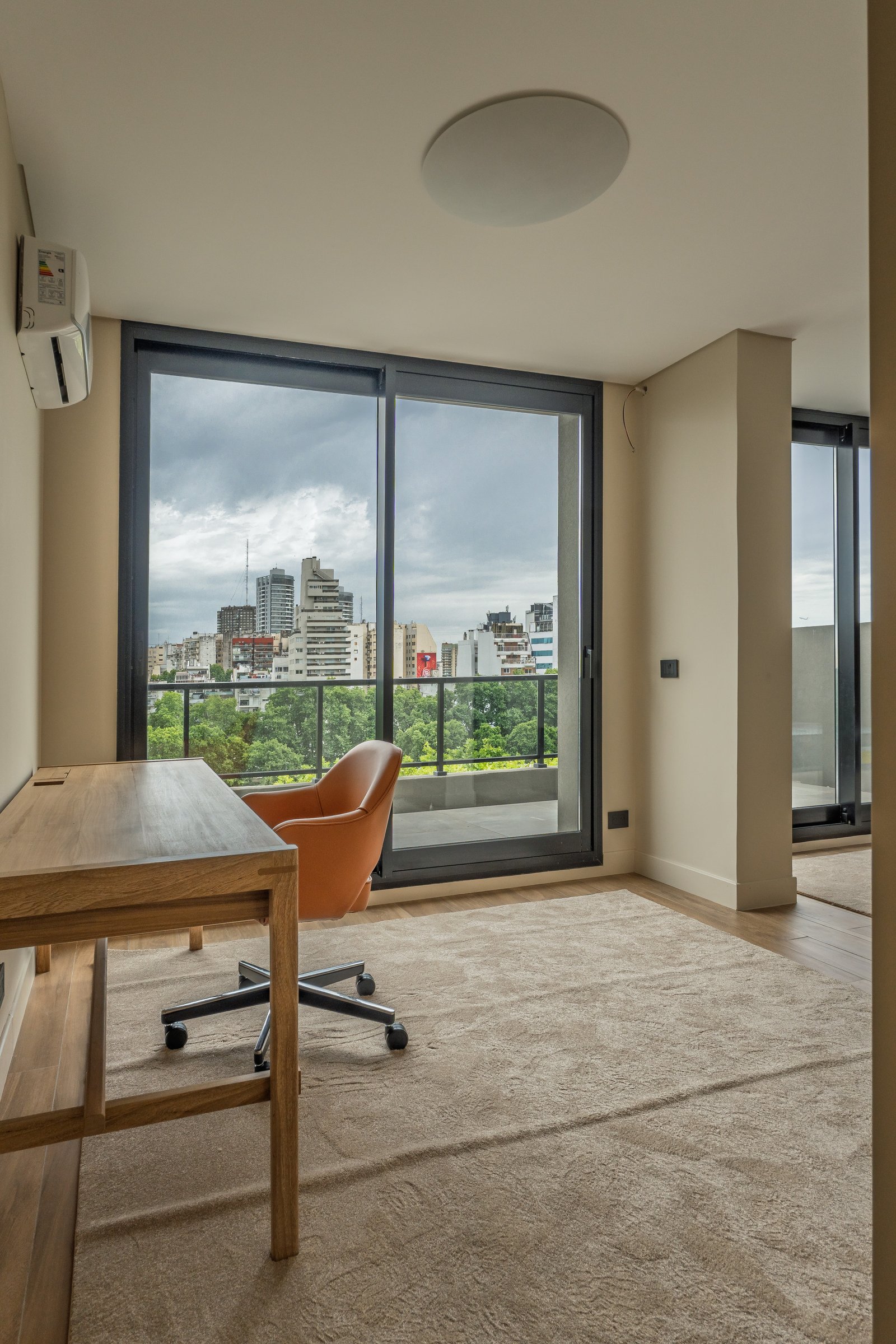 Escritório moderno com mesa de madeira e poltrona laranja — projeto Godoy Cruz, por ABEJA CONCEPT, em Palermo