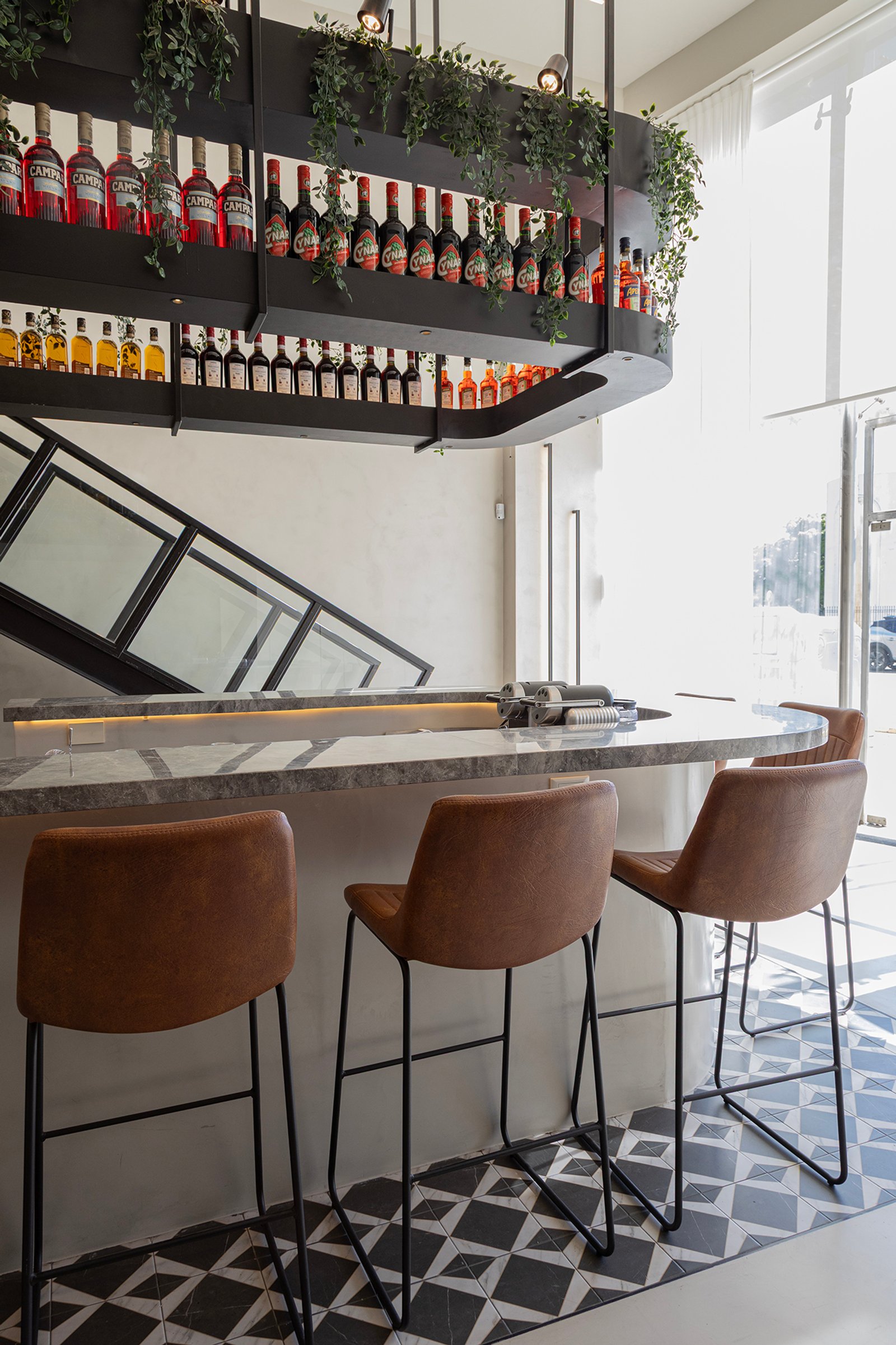 Bar moderno com prateleiras suspensas de garrafas e bancos de couro — projeto HATSU Núñez - MZV Arquitectura, por Gaby Alfonso, em Buenos Aires