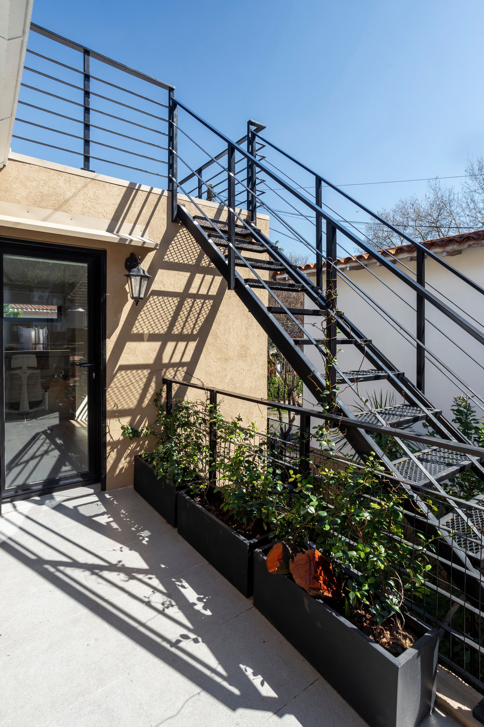 terraza exterior con escalera de metal y macetas — proyecto LAPRIDA, por La Nave Arq., en Vicente López