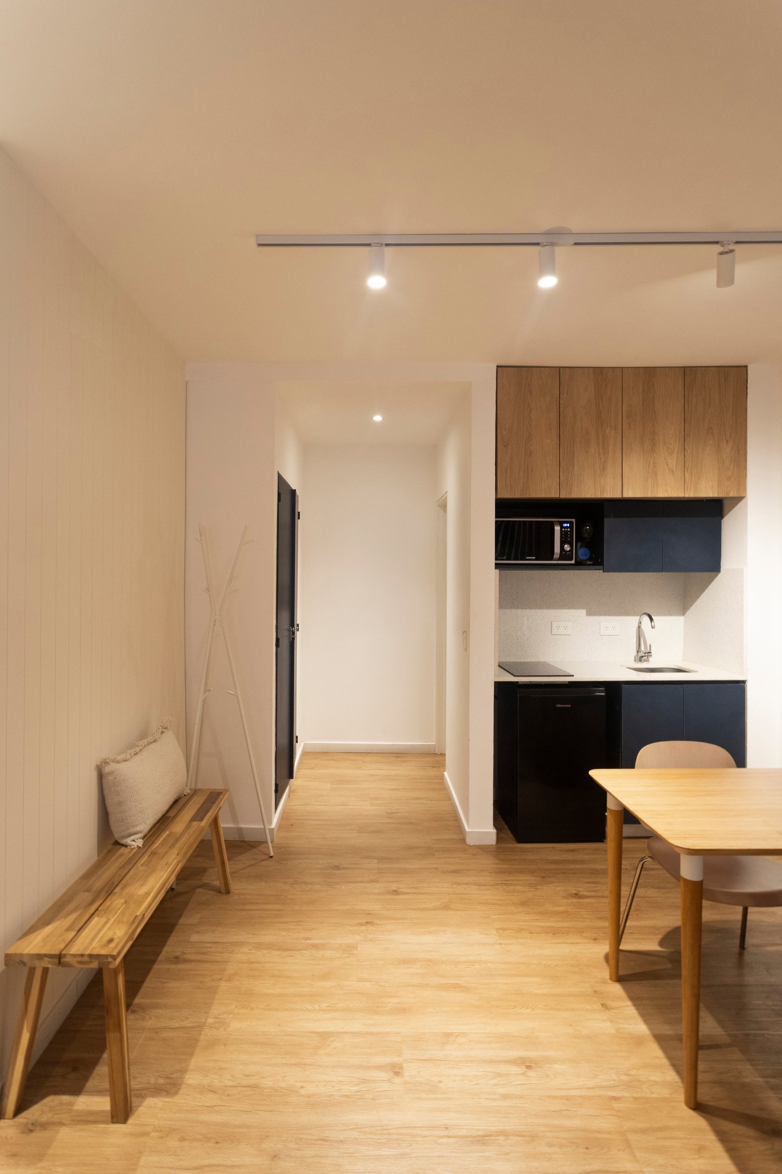 Studio moderno com cozinha integrada e banco de madeira — projeto REFORMA NE, por Rastro Estudio, em Palermo
