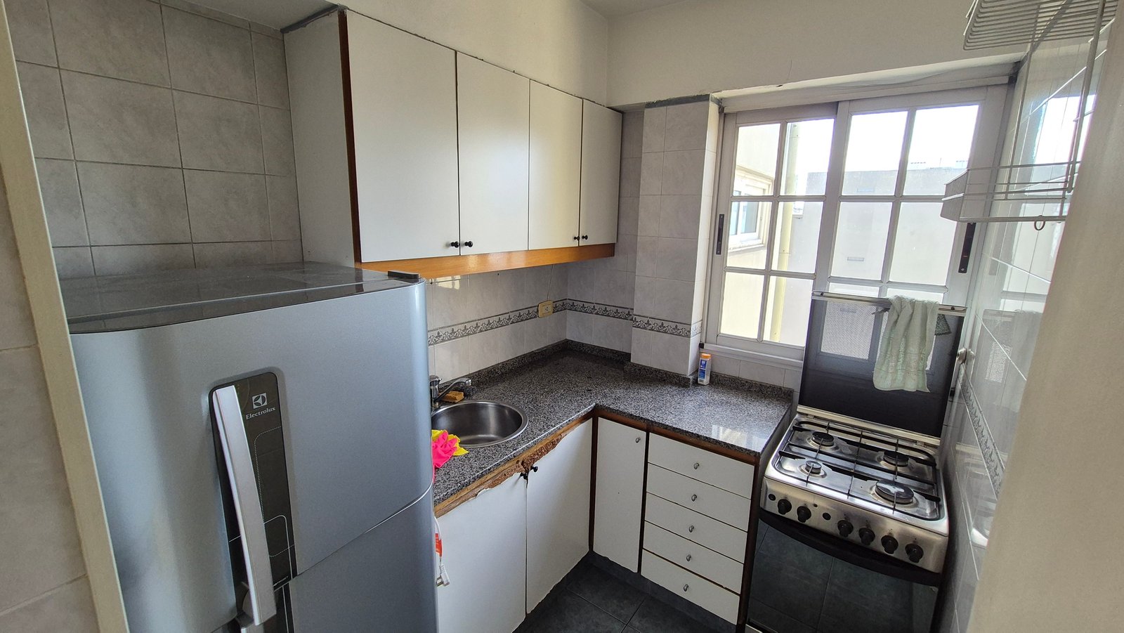 Cocina compacta moderna con electrodomésticos de acero inoxidable y azulejos blancos — proyecto Cocina - Remodelación Soho, por RenovArqui, en Palermo