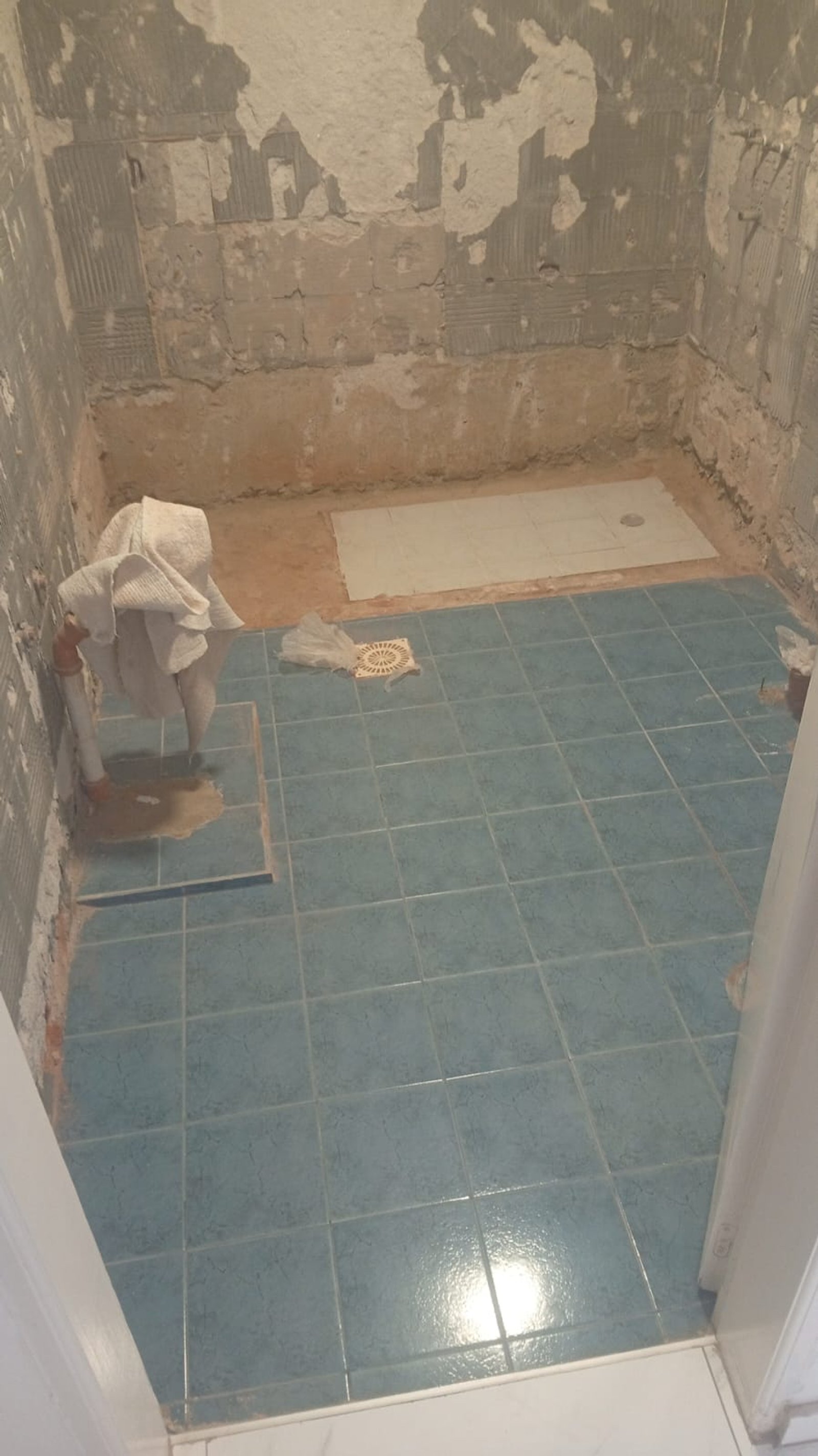 Baño en construcción con azulejos azules y paredes de concreto — proyecto Remodelación de baño, por CN Construcciones, en Alta Gracia
