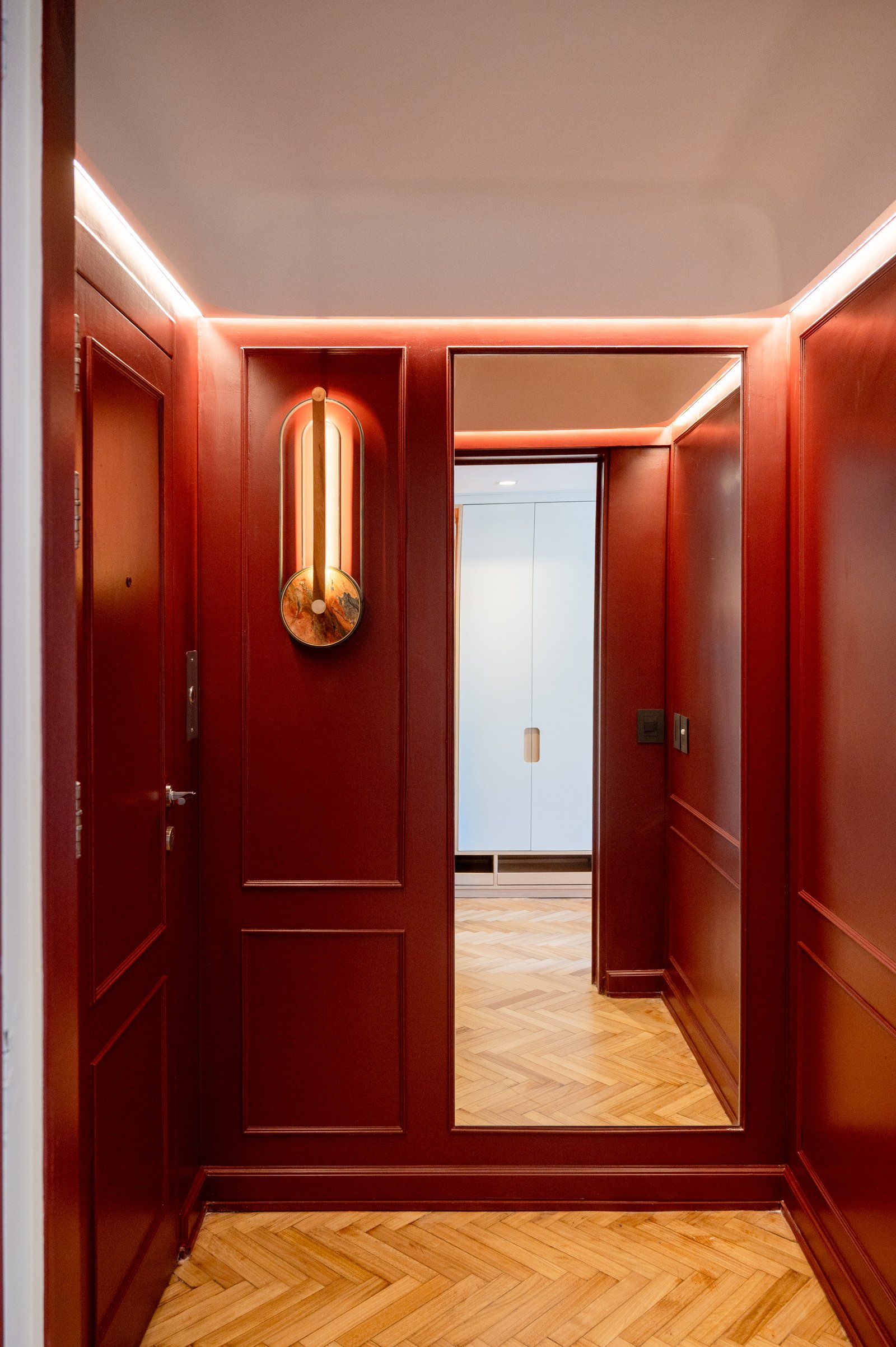 Pasillo lujoso de madera roja con piso de parqué y luz tenue — proyecto ALVEAR TYM, por AB ARQUITECTURA, en Recoleta