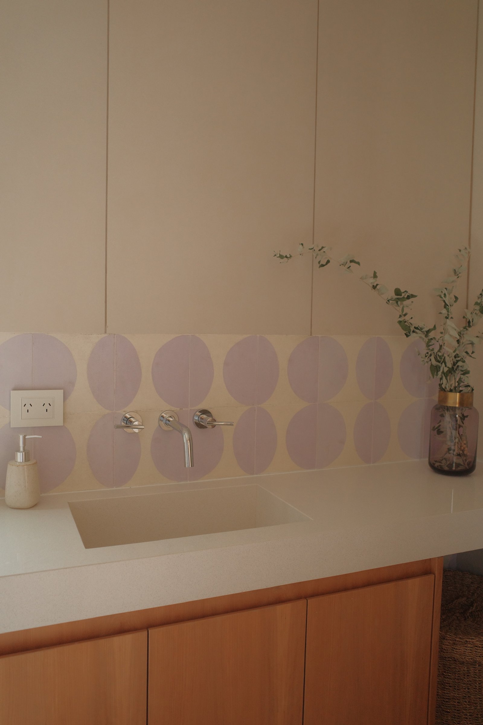 Baño moderno con bacha integrada, grifería cromada y revestimiento circular — proyecto Casa Refugio, por Jeitinho Estudió Creativo, en Neuquén