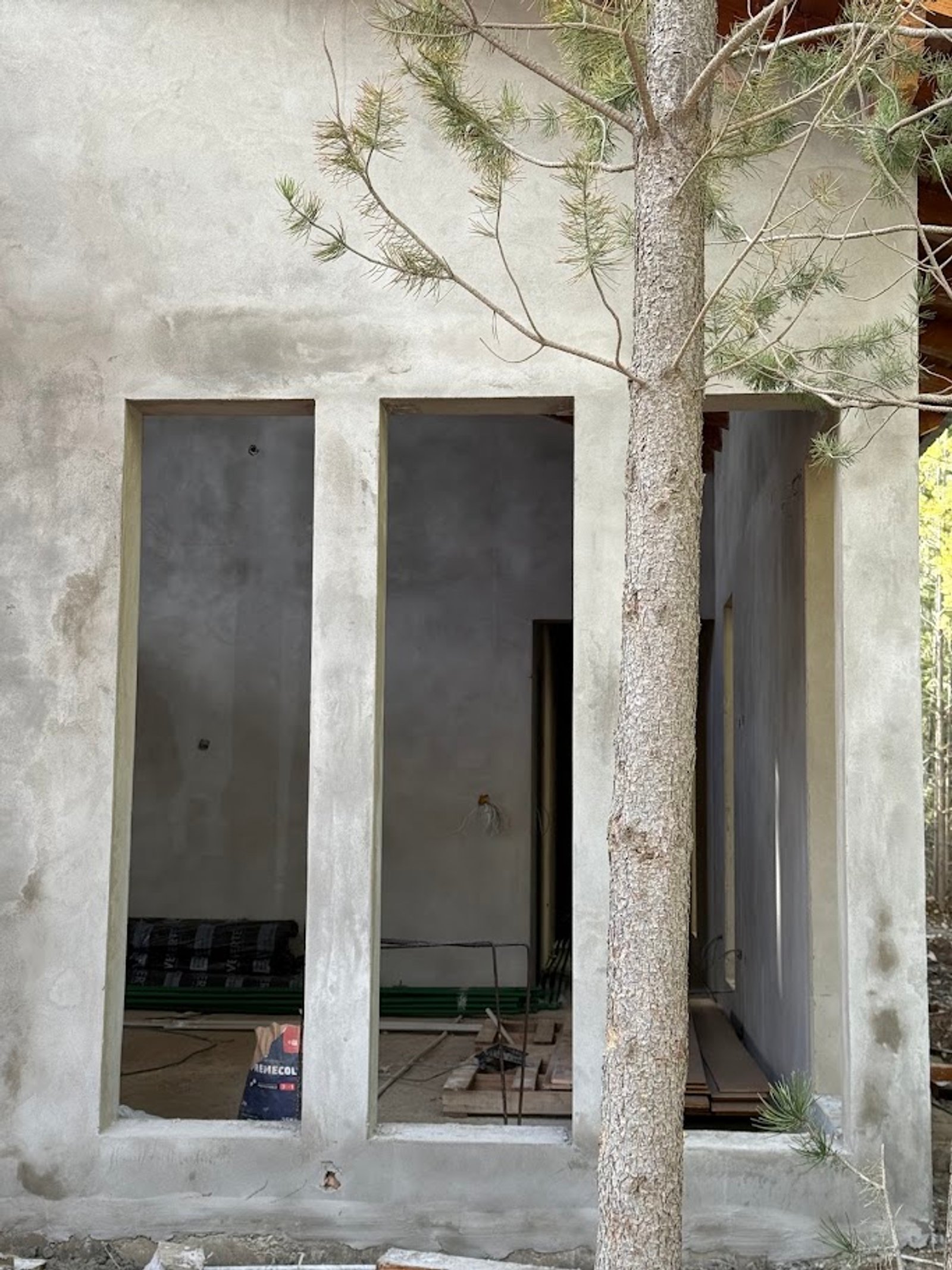 obra en construccion con arbol atravesando estructura — proyecto Casa Q11, por Showhouse Bariloche, en San Carlos de Bariloche