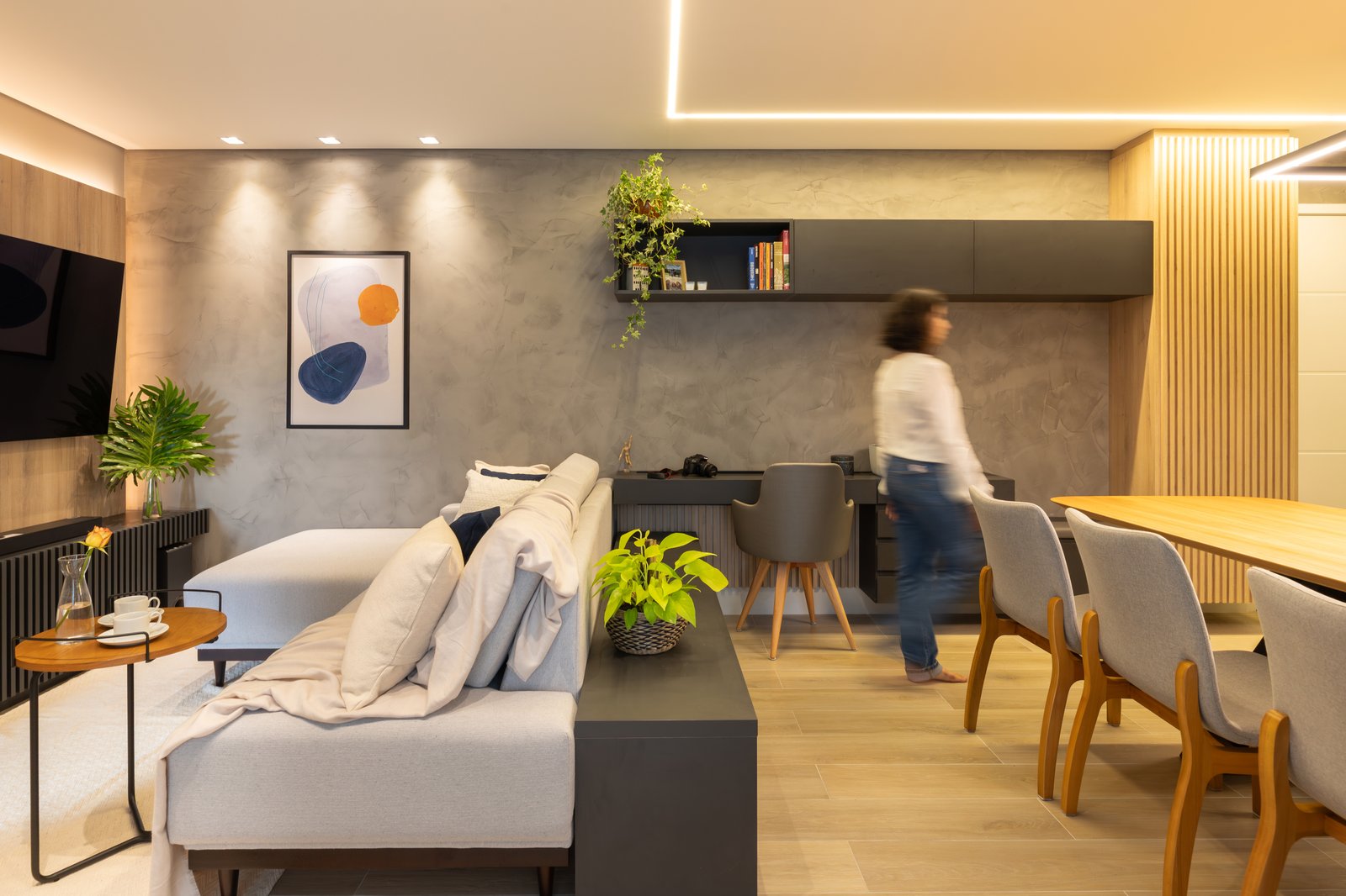 Sala de estar moderna com sofá curvo cinza e parede de microcimento — projeto Apartamento VC - São Caetano, por EBBA Arquitetura, em São Caetano do Sul