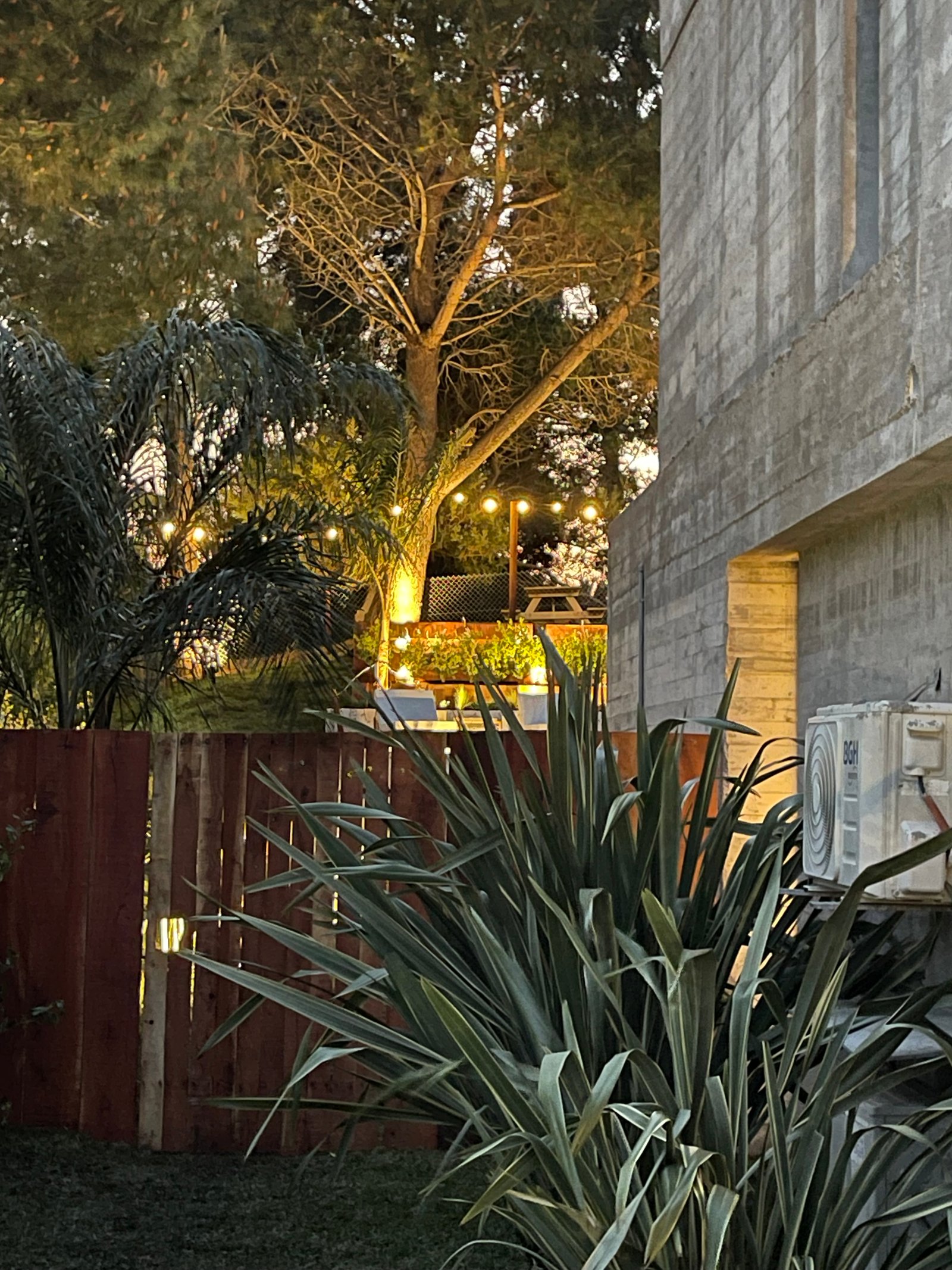 Fachada moderna de concreto con jardín y luces exteriores — proyecto COSTA ESMERALDA, por Baires Green, en Pinamar
