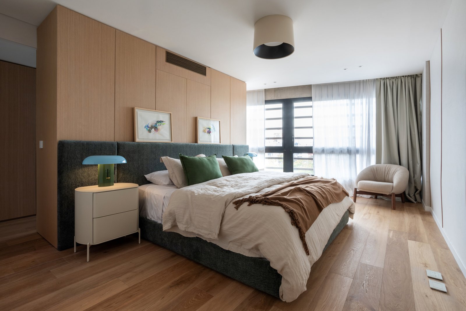 Quarto moderno com painéis de madeira, cama azul e poltrona branca — projeto Vidal, por Estudio Losa, em Belgrano