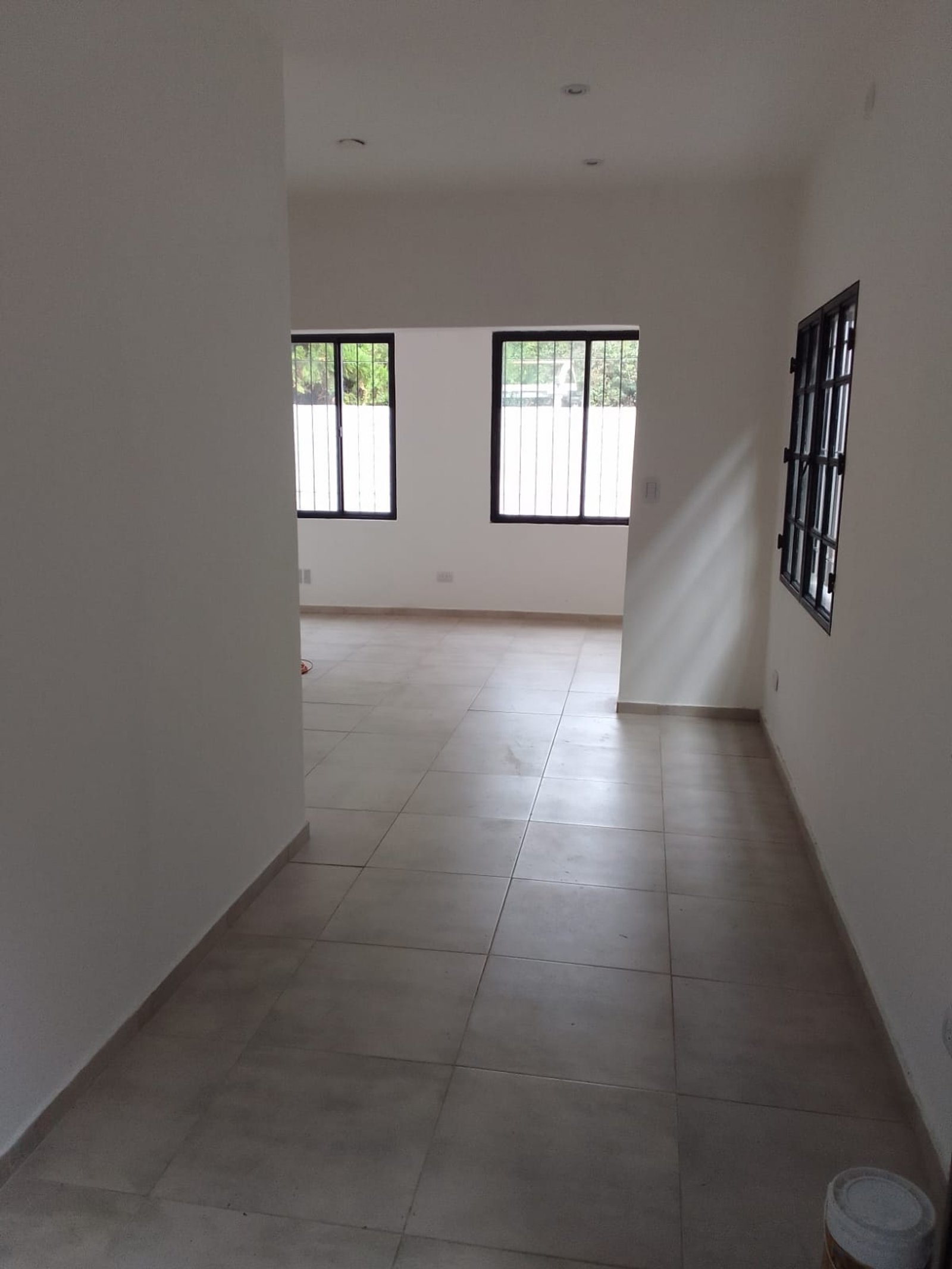 Pasillo interior con piso de cerámica gris y paredes blancas — proyecto Casa en Sarandi, por Arquitecto Guido Niccoli, en B1872 Sarandí