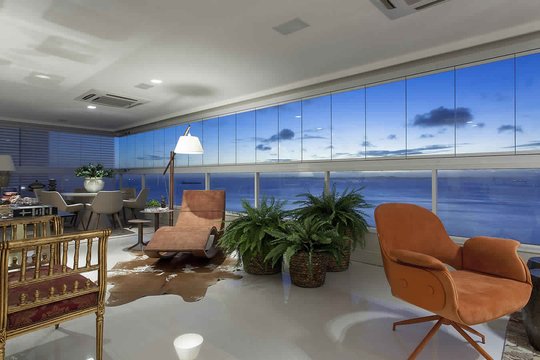 Terraza moderna con vista al mar, sillones terracota y ventanales amplios — proyecto Varandas, por Xico Diniz