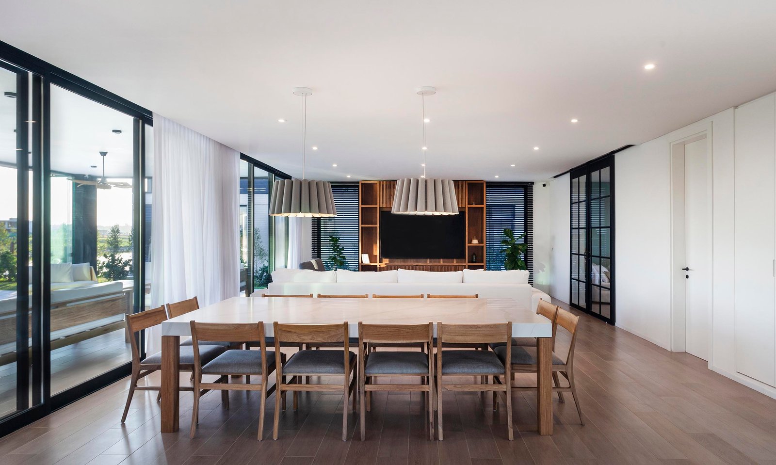 Comedor moderno y luminoso con ventanales y luces tejidas — proyecto CASA C313, por A'PRIMA - Arquitectura Sustentable, en Provincia de Buenos Aires