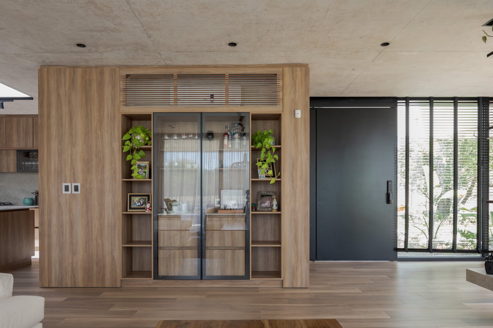 Sala de estar com parede de madeira e portas de correr pretas — projeto Casa PLANALTO, por Grupo CRBN, em Av. Pres. Perón 10298