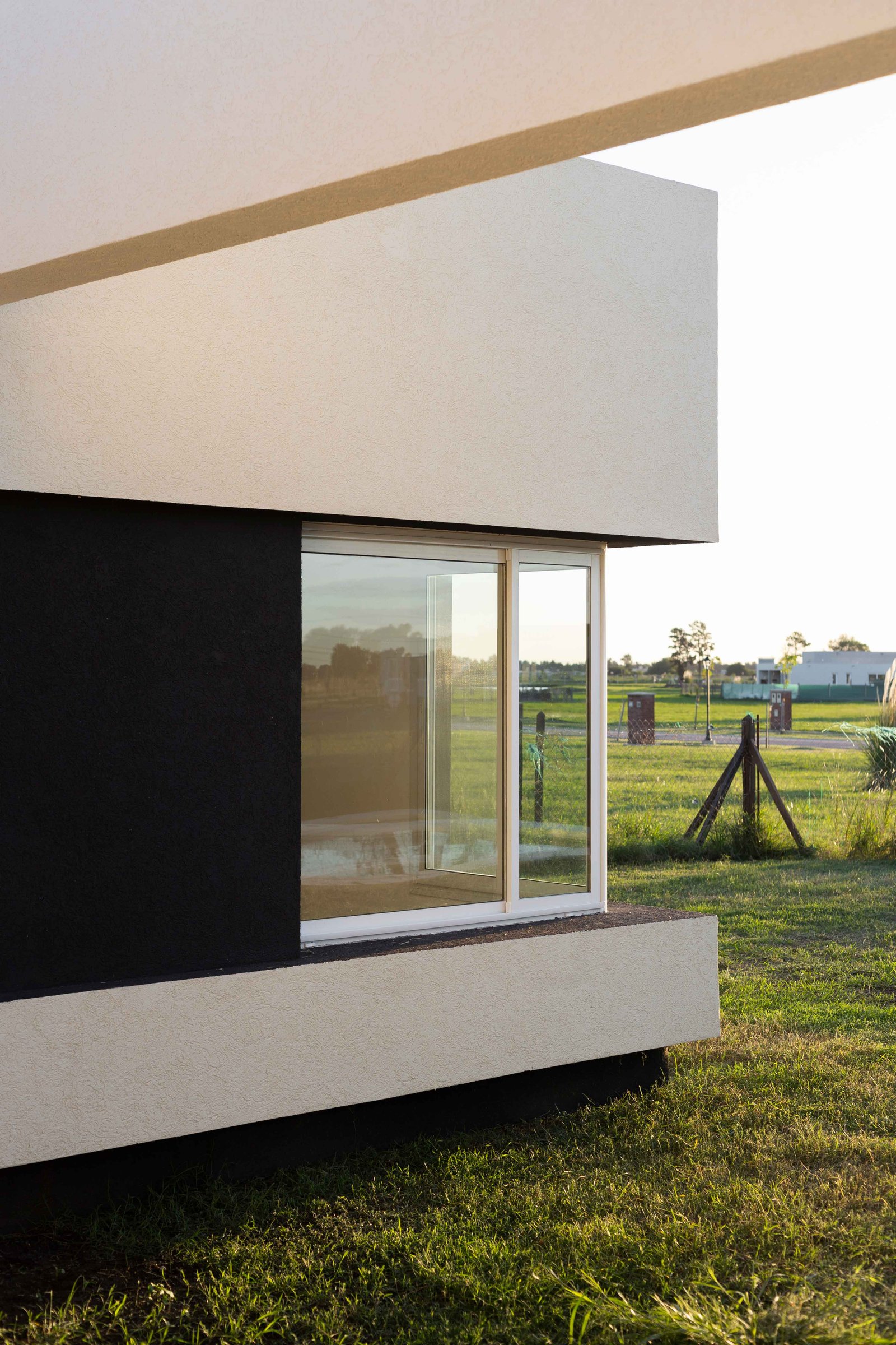fachada moderna con grandes ventanales y contraste blanco y negro — proyecto San Simon I, por Estudio Stepa, en Ezeiza