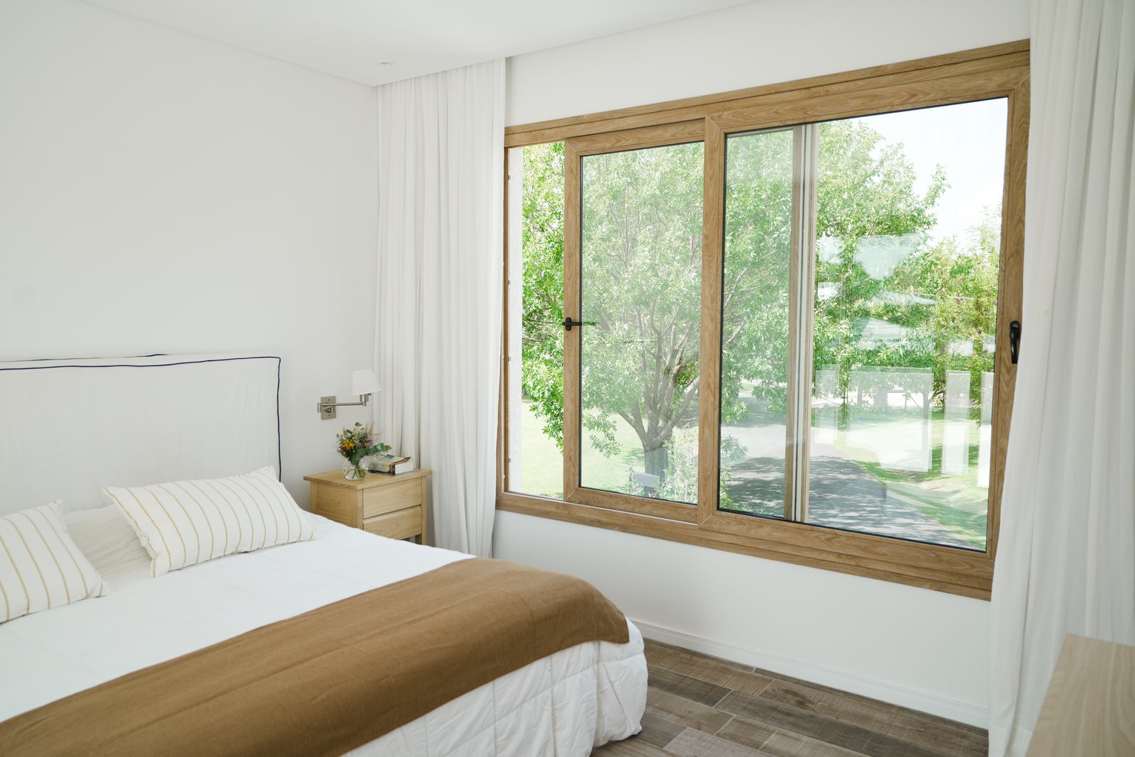 Dormitorio moderno con gran ventanal y vista al jardín — proyecto Habitaciones, por CASA1-TROMEN, en Bella Vista