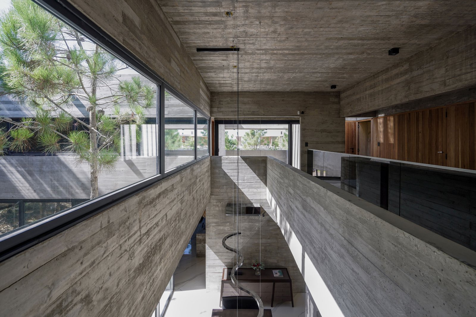 Interior moderno de hormigón con escalera caracol y gran altura — proyecto Casa 4H, por Besonías Almeida arquitectos, en X6VF+67