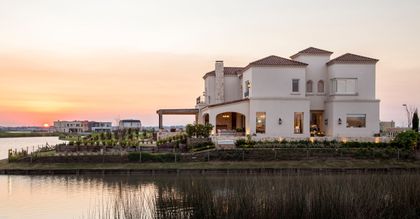 Casa mediterránea frente al agua al atardecer — proyecto Casa MF, por Estudio Junor, en Belén de Escobar