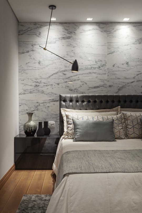Dormitorio minimalista con cabecero de cuero, pared de mármol blanco y lámpara colgante negra — proyecto CASA HB, por Frederico Bicalho Arquitetura