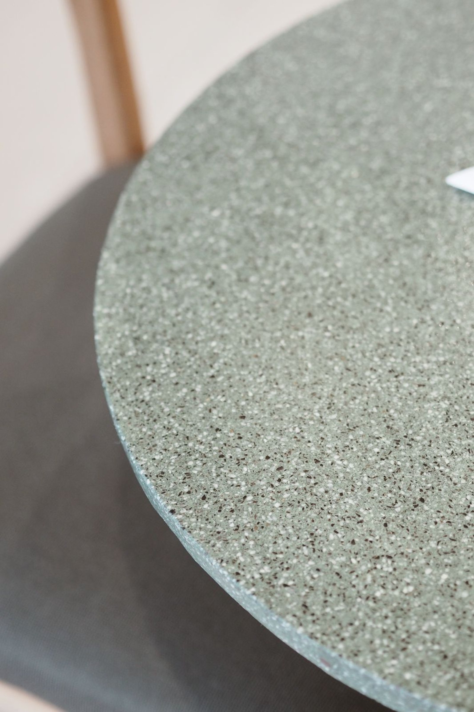 Mesa redonda de terrazo gris verdoso junto a silla oscura en comedor moderno — proyecto FOMO CAFÉ, por APATHEIA, en Vicente López