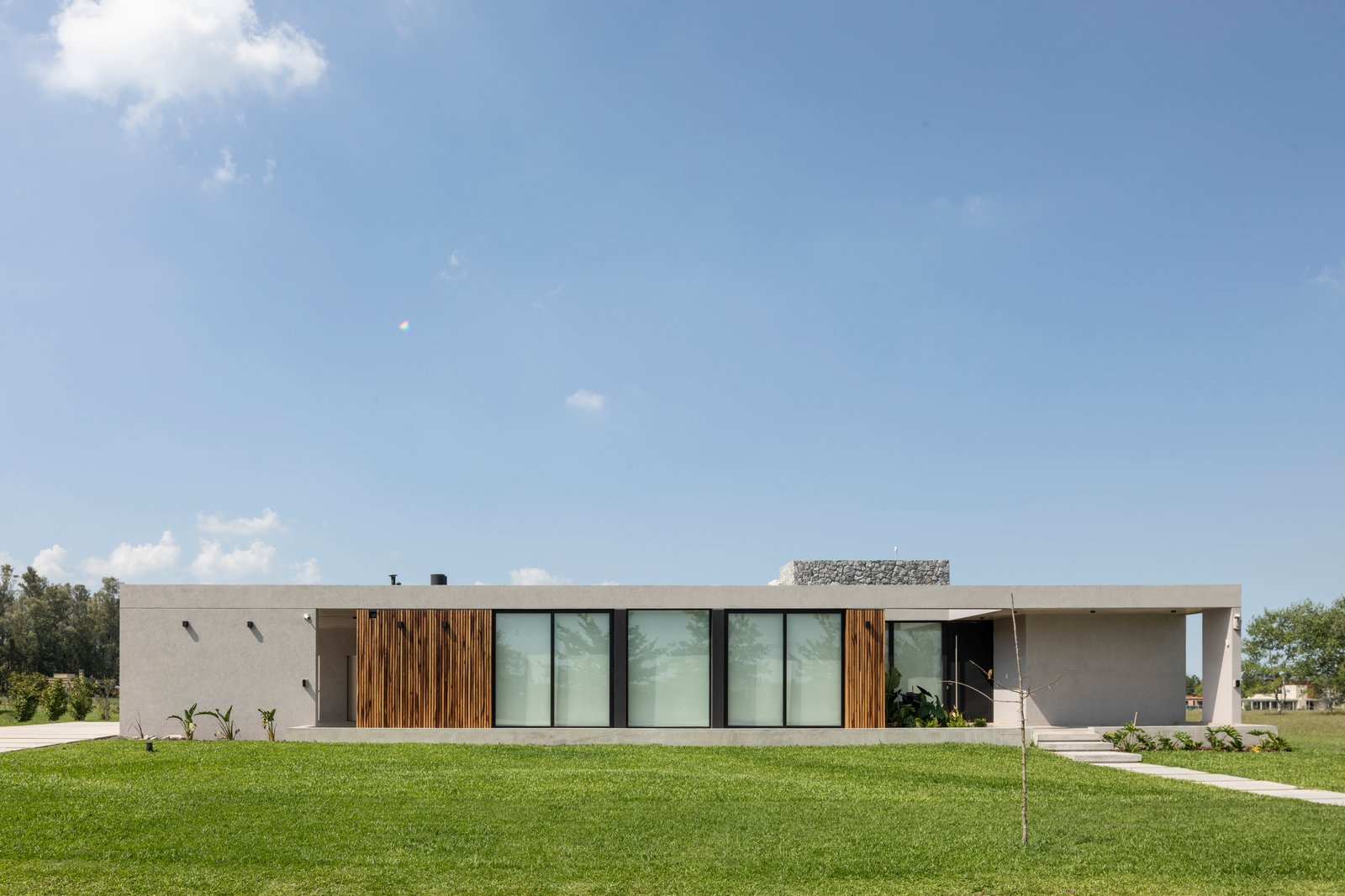 fachada moderna minimalista con madera y amplios ventanales — proyecto Casa Cruz , por Grupo CRBN, en B2812 Exaltación de la Cruz