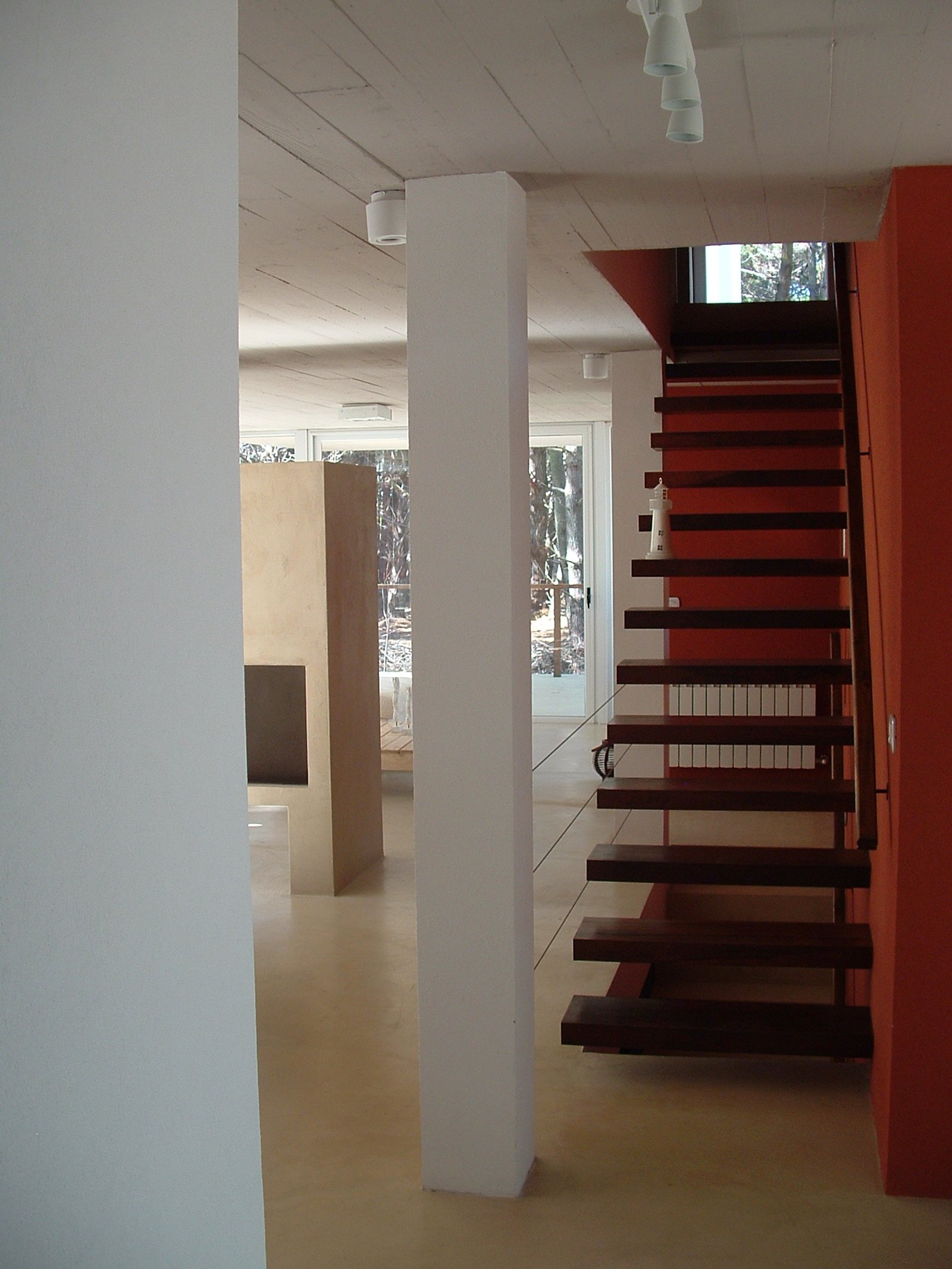 escalera flotante moderna con pared naranja y microcemento — proyecto villa del puente, por GJF estudio, en Costa del Este