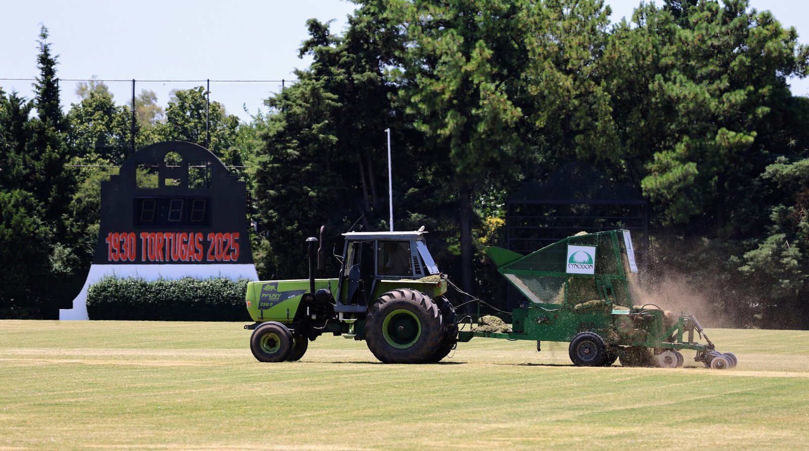 Tractor cosechando pasto en un campo frente a un marcador — proyecto Row Planting Tortugas, por Cynodon, en Au Panamericana