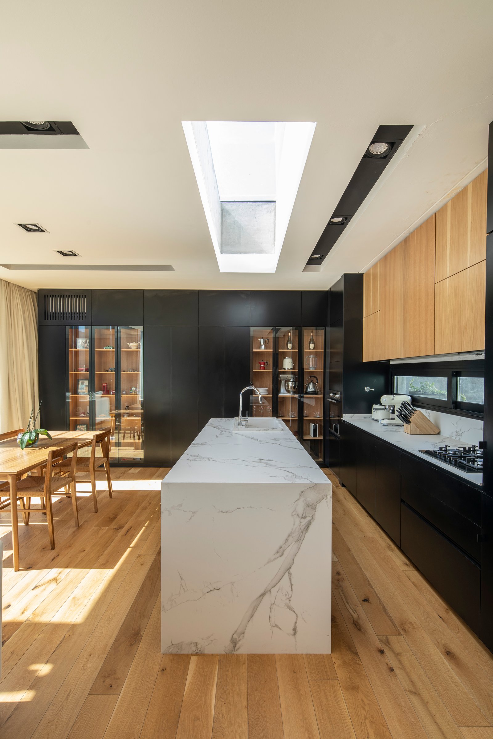 Cozinha moderna com ilha grande de mármore e claraboia — projeto Casa MECHA, por Grupo CRBN, em B1712 Castelar