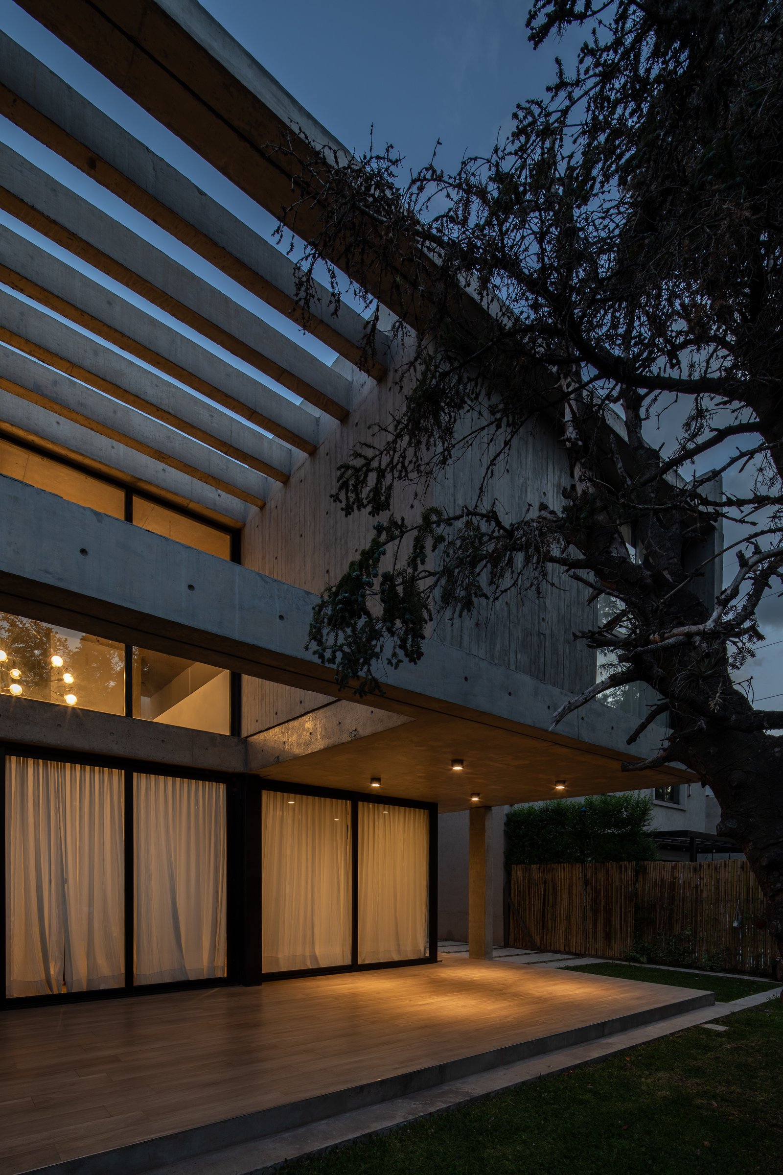 Fachada moderna con pérgola de hormigón y deck de madera — proyecto Casa Emilia, por Grupo CRBN, en Parque Leloir