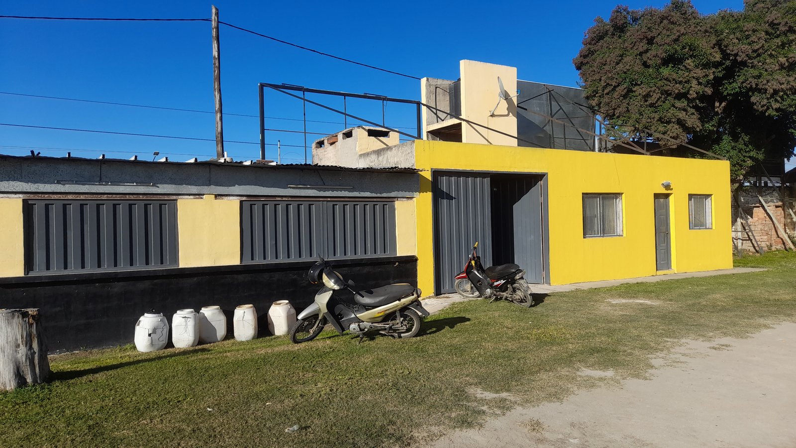 fachada amarela moderna com revestimento de metal cinza — projeto Remodelación Bodegón del depo, por CN Construcciones, em Alta Gracia