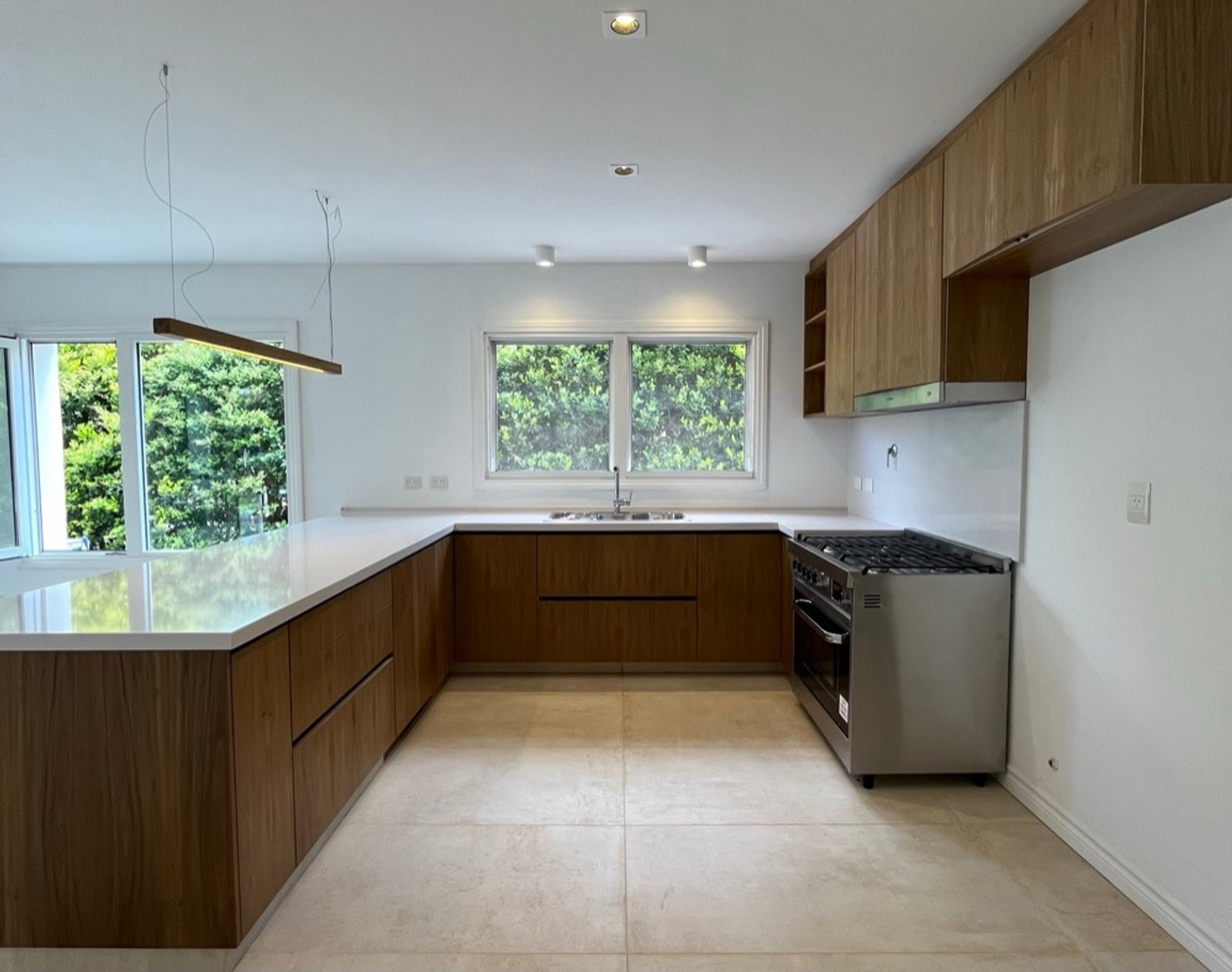 Cocina moderna con muebles de madera natural y grandes ventanales — proyecto Reforma integral Vivienda., por Arcucci Arquitectura, en Campo Grande