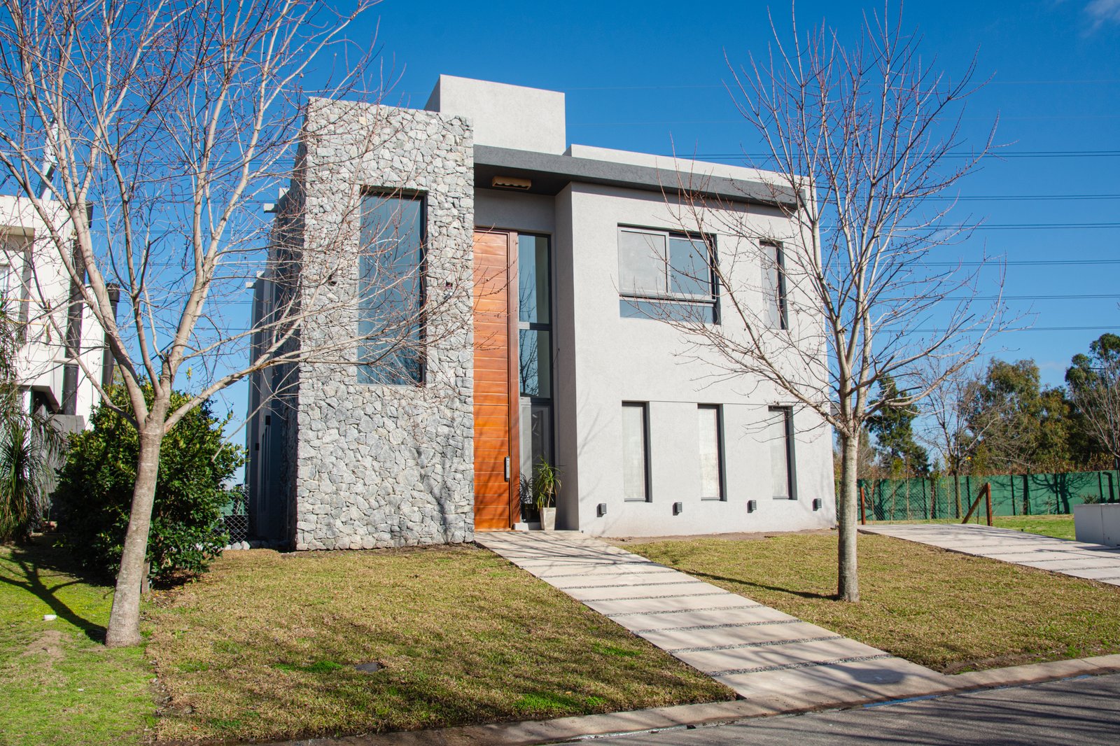Casa moderna con fachada de piedra gris y grandes ventanales — proyecto Casa Tipas, por MSMC, en Сармьенто 3830