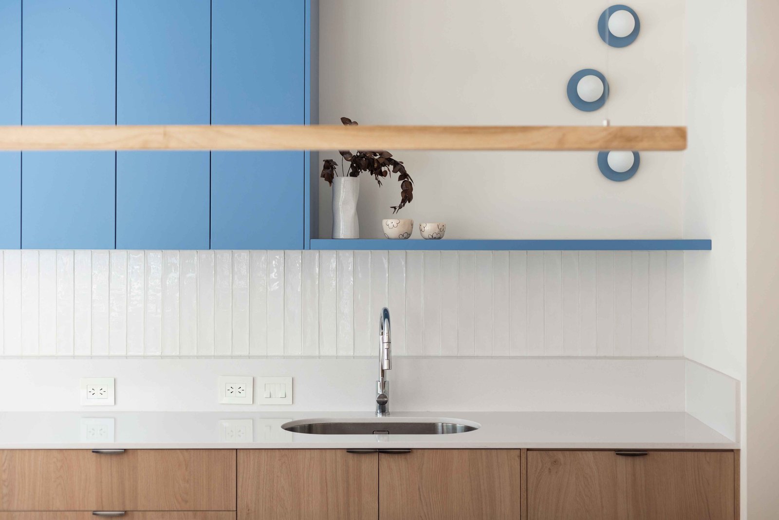 Cocina moderna con muebles altos azules y bajomesada de madera — proyecto Grecia, por Bouré Studio, en Núñez