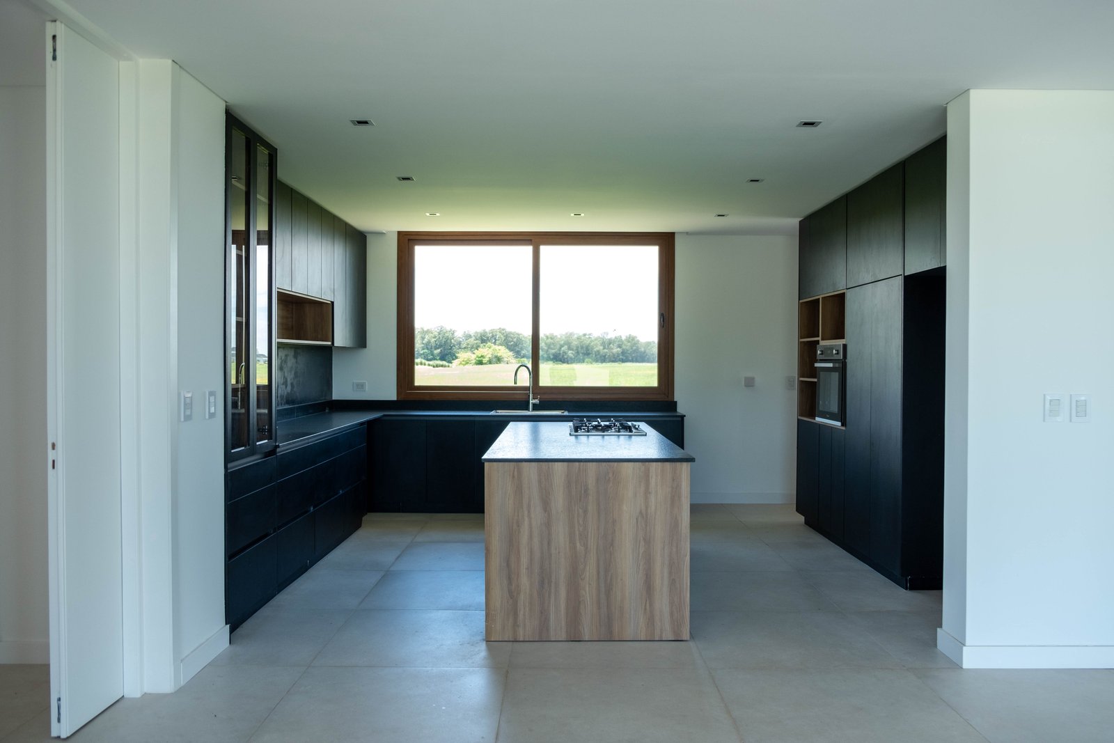 Cozinha moderna com ilha central e janelas amplas — projeto CASA GOLF, por SEDE Arq., em Av. Pereda S/N