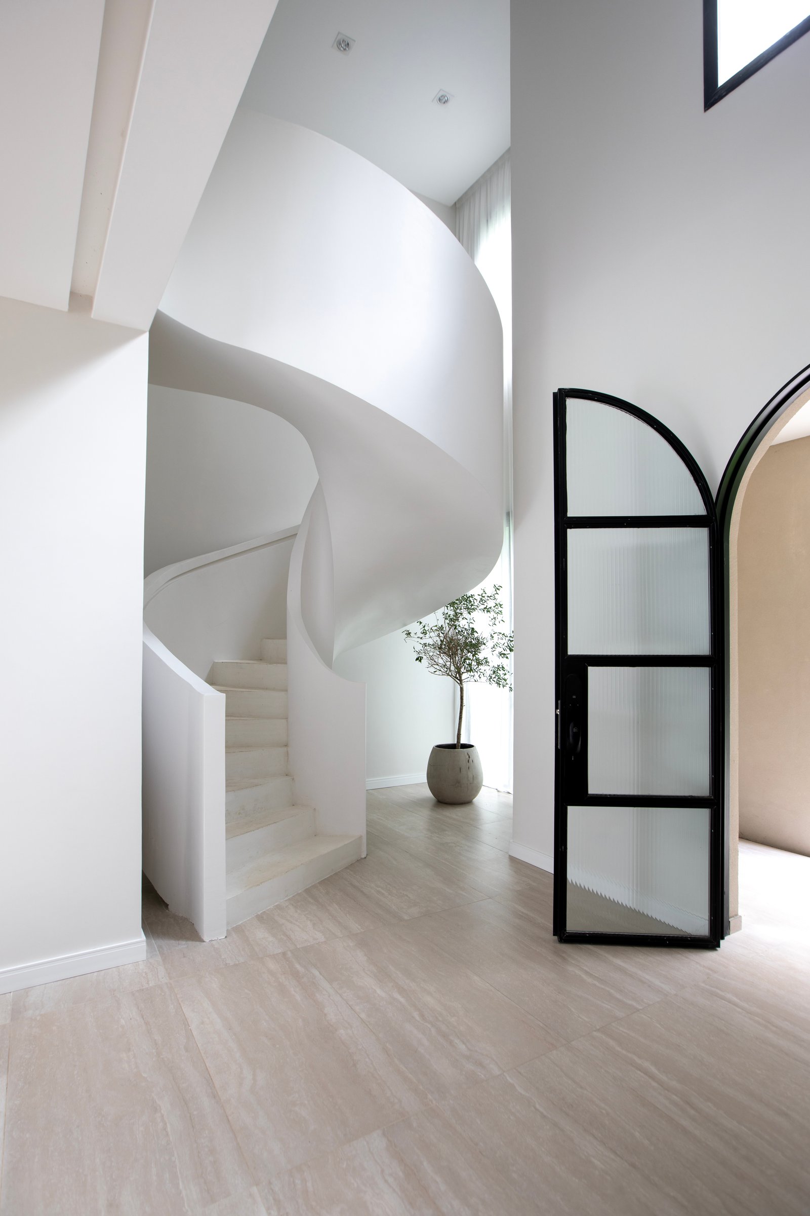 Escalera caracol blanca con pared curva y puerta de metal — proyecto OBRA TRAVERTINO BEIGE, por ILVA, en Provincia de Buenos Aires