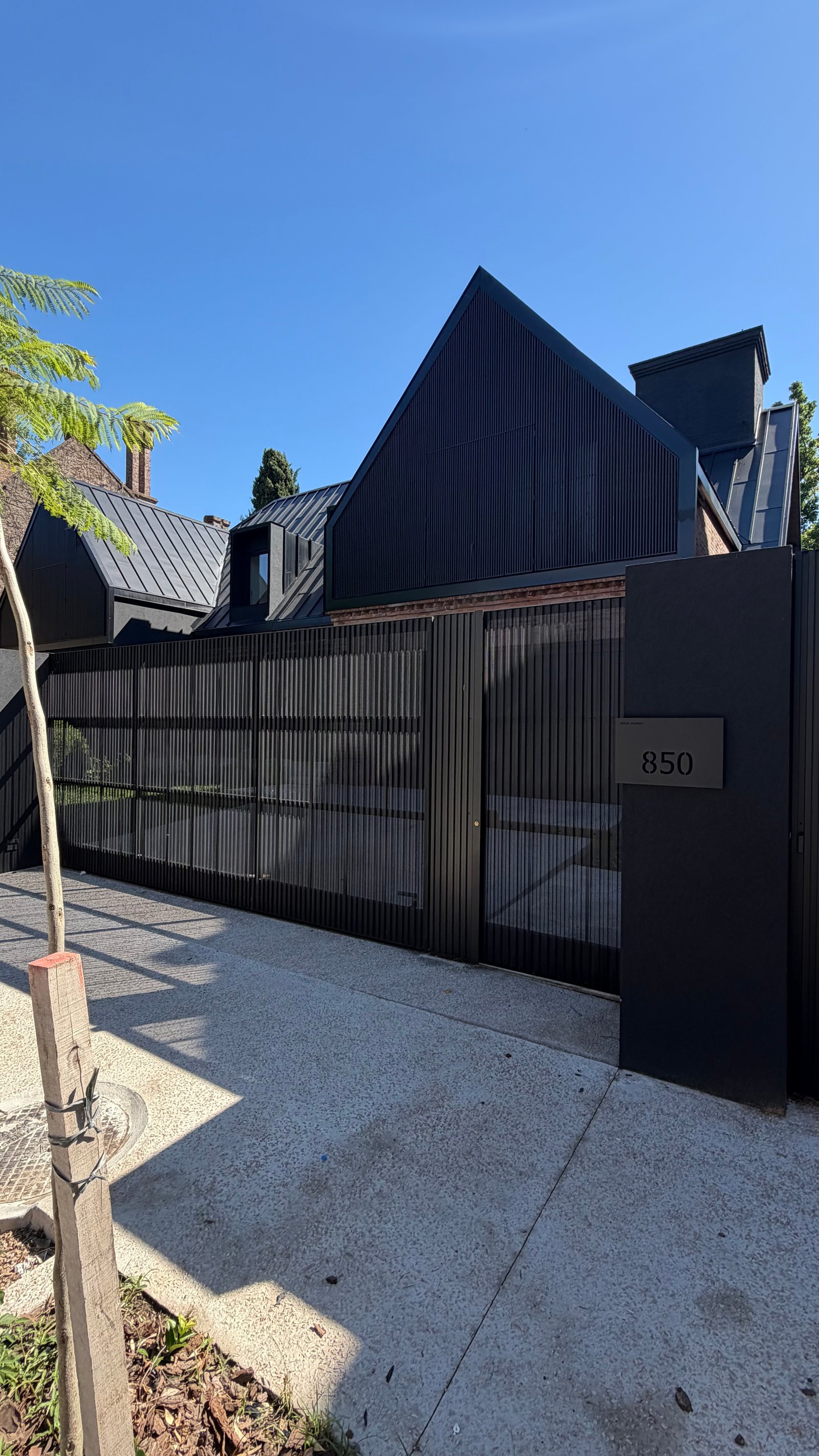 Fachada moderna de casa con techo angular y portón de lamas verticales — proyecto Casa JCP, por radovic_arquitecto, en José C. Paz 850
