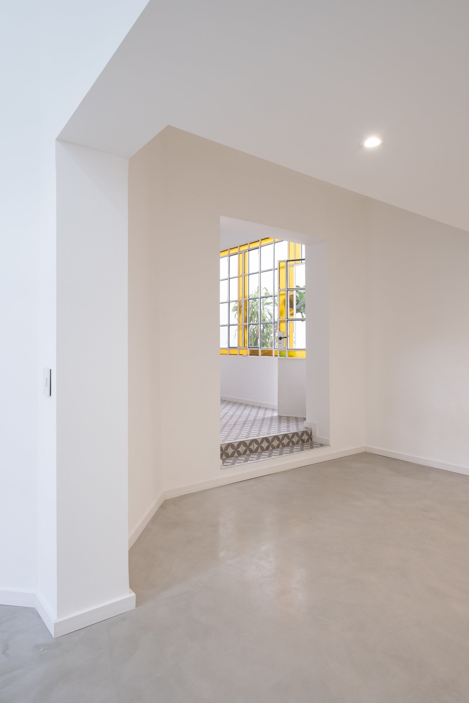 Espacio moderno con escaleras de azulejos y grandes ventanas amarillas — proyecto Casa Patio, por Herrera Ungaro, en San Cristóbal