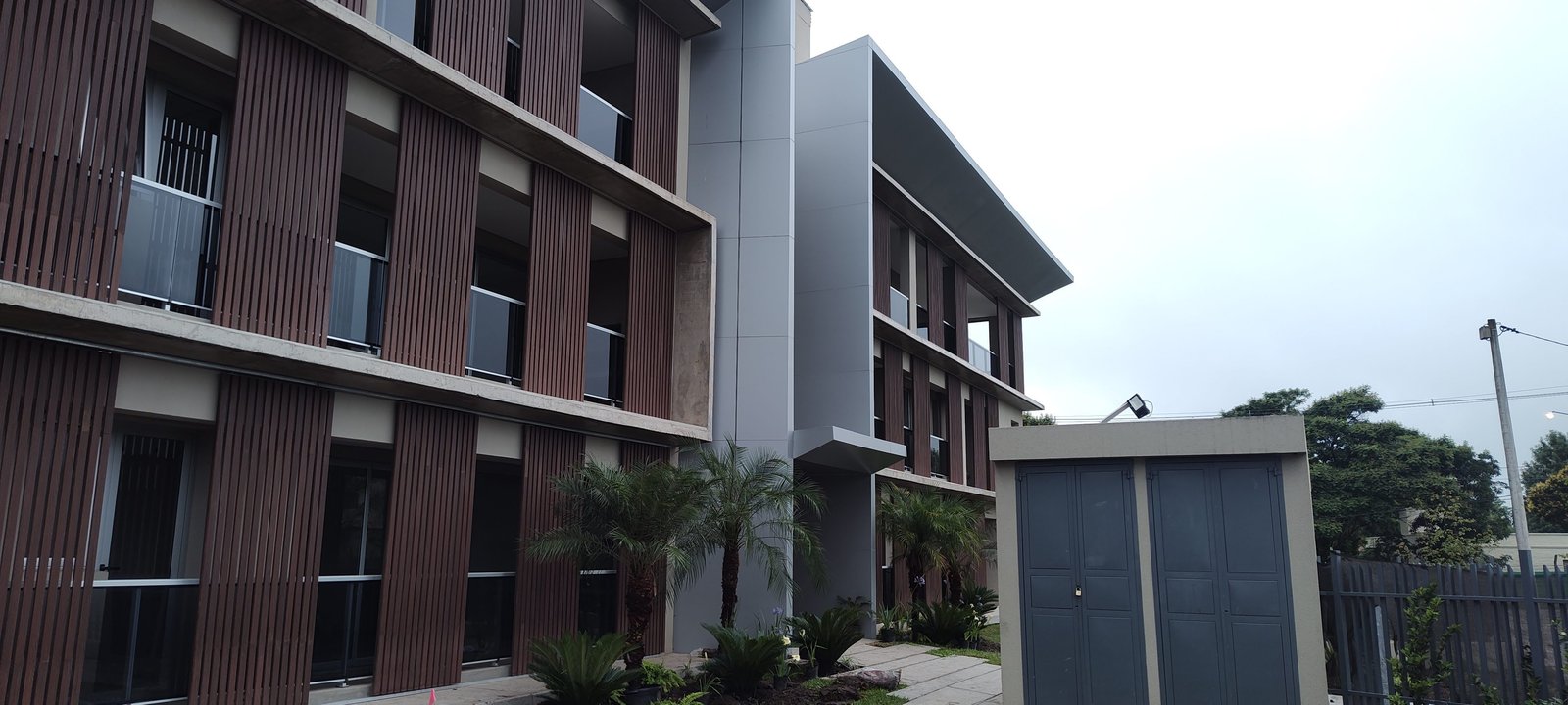 Fachada moderna con revestimiento de madera y grandes ventanales — proyecto EDIFICIO CHUBUT, por HMCONSTRUCCIONES, en Chubut